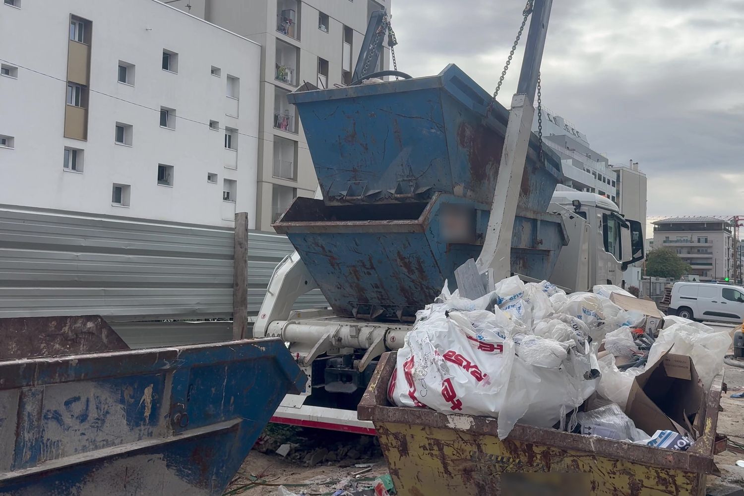 Camion de levage chargeant une benne de déchets triés sur le chantier