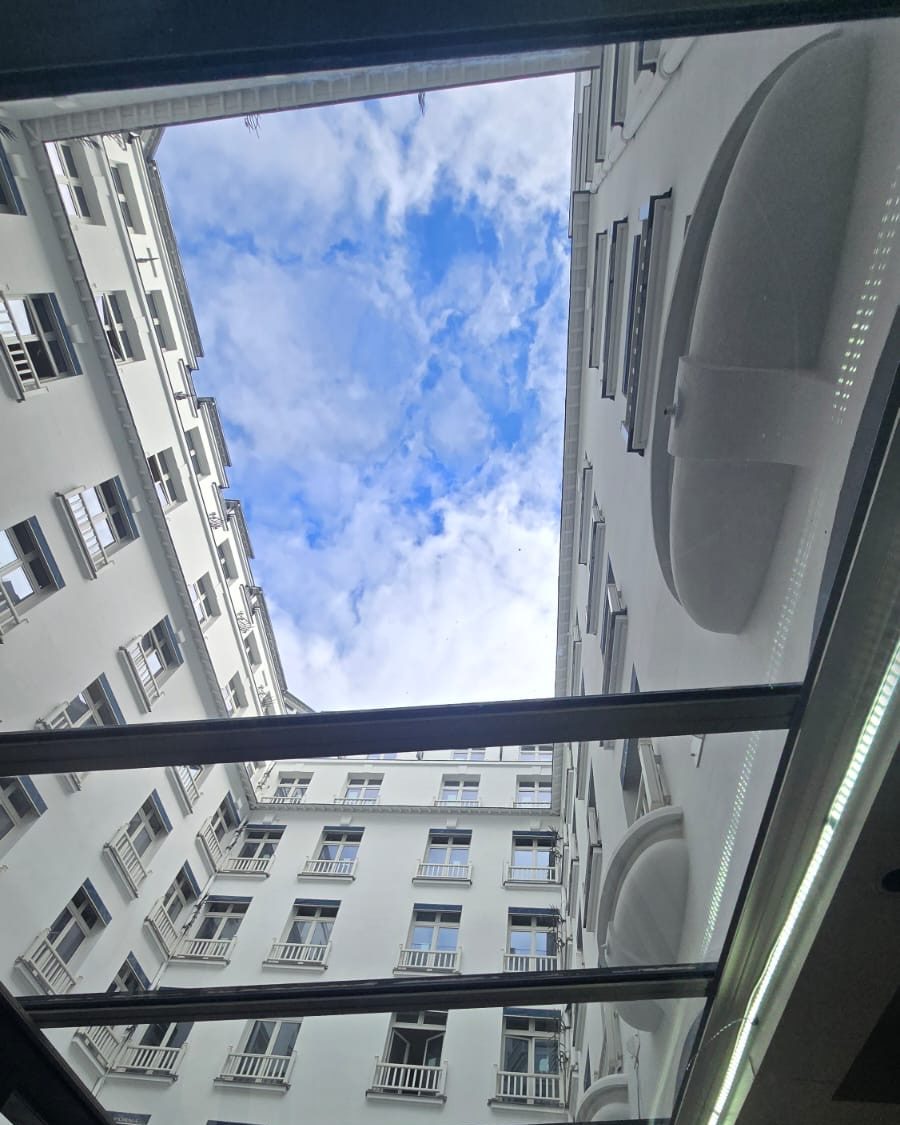 Verrière d’un hôtel parisien vue de l’intérieur, le ciel visible à travers le vitrage