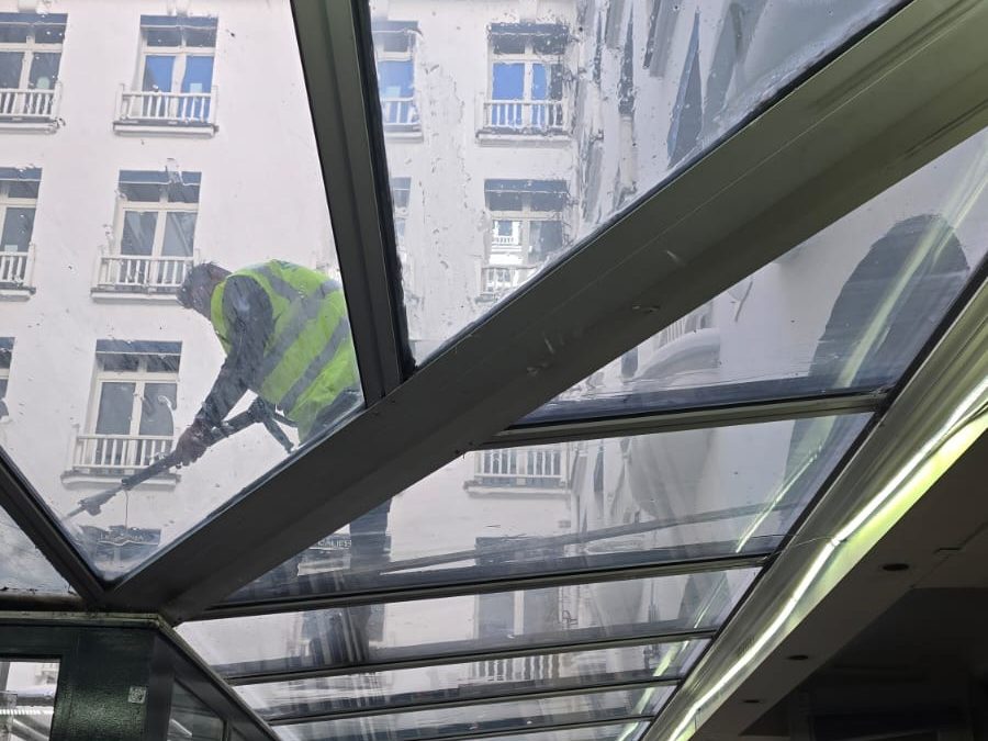 Agent nettoyant la verrière d’un hôtel, vu à travers le vitrage